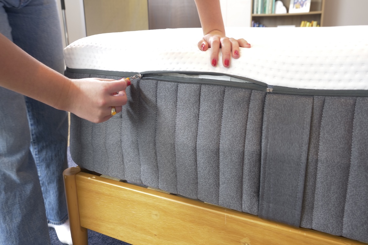  Woman’s hands pulling the zipper on the Emma Hybrid Comfort mattress cover.