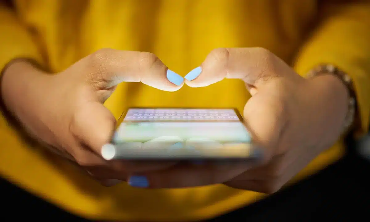 Woman in yellow top obsessively using her phone, highlighting the 